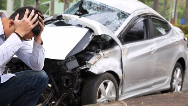 white-car-totaled-man-crouched-by-tree-mst